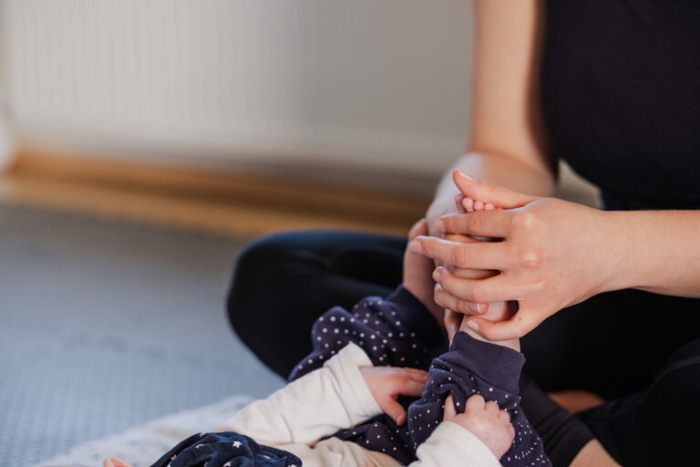 Mama massiert Babyfüße beim Babyyoga