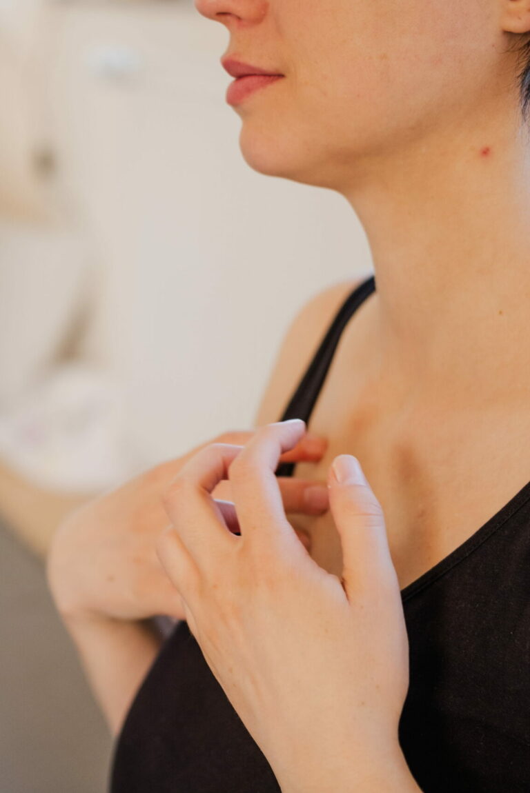 Nahaufnahme von Frauenhänden, die sich am Schlüsselbein klopft