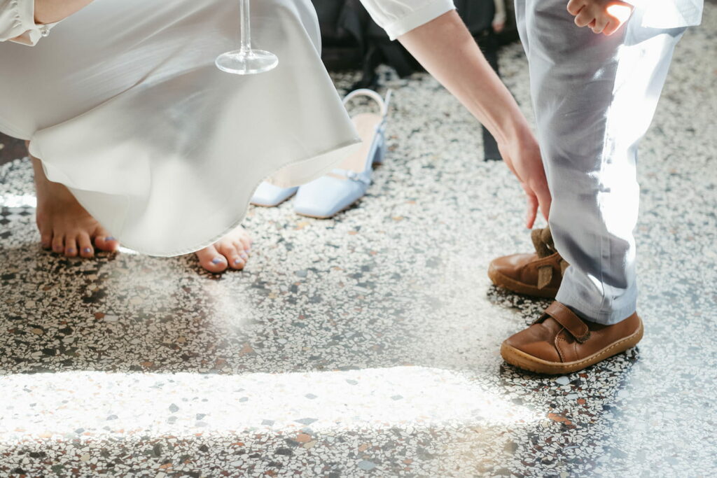Braut hilft Kind beim Schuhe ausziehen